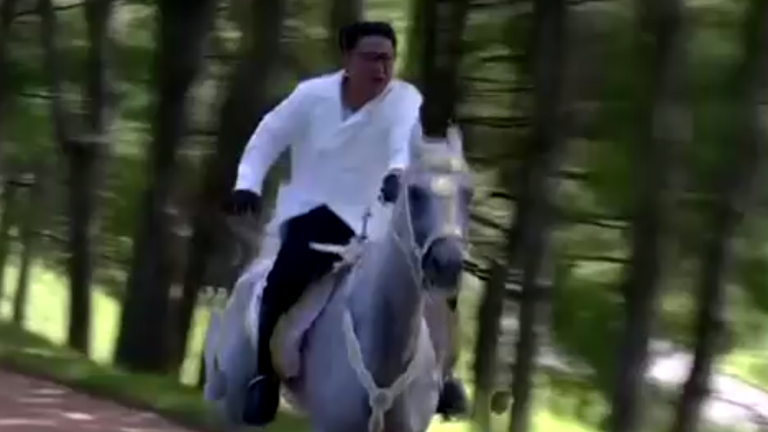 Kim gallops through a wood on a white horse