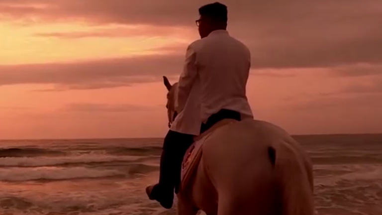 The North Korean leader is shot from behind on a beach at sunrise