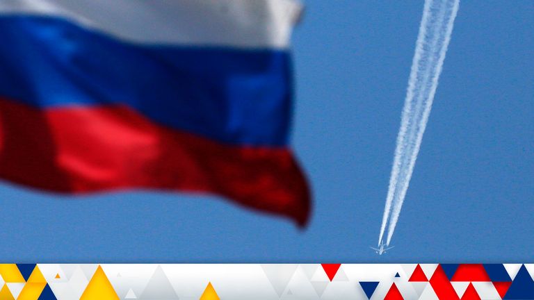 A contrail left by a passenger plane is seen behind a Russian state flag as it passes over the Siberian city of Krasnoyarsk, August 7, 2014. Russian Prime Minister Dmitry Medvedev said on Thursday that Moscow was considering banning transit flights by airlines from the European Union and the United States to the Asia-Pacific region. REUTERS/Ilya Naymushin (RUSSIA - Tags: POLITICS TRANSPORT BUSINESS)

