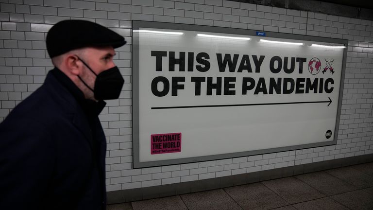 A man wearing a face mask walks past a health campaign poster in London. Pic: AP