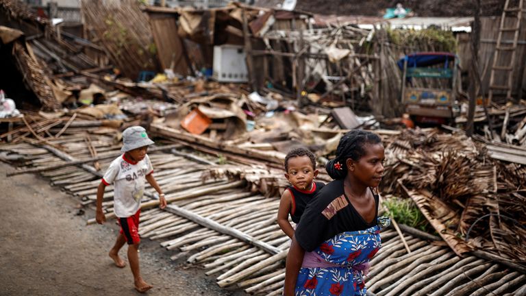 A woman and her children walk past destroyed houses, in the aftermath of Cyclone Batsirai, in the town of Mananjary, Madagascar, February 8, 2022. REUTERS/Alkis Konstantinidis
