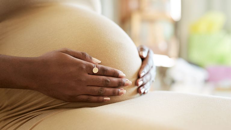 Shot of a mother to be caressing her baby bump stock photo