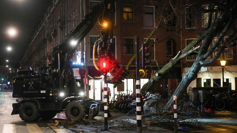Workers remove an uprooted tree in Amsterdam, the Netherlands, Friday, Feb. 18, 2022. The second major storm in three days has battered northern Europe, killing at least four people.  Photo: AP