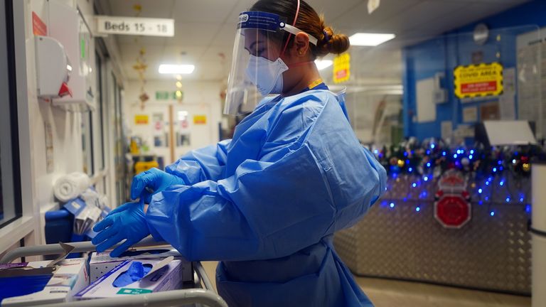 A nurse puts on PPE on a ward for Covid patients at King&#39;s College Hospital, in south east London. Picture date: Tuesday December 21, 2021.