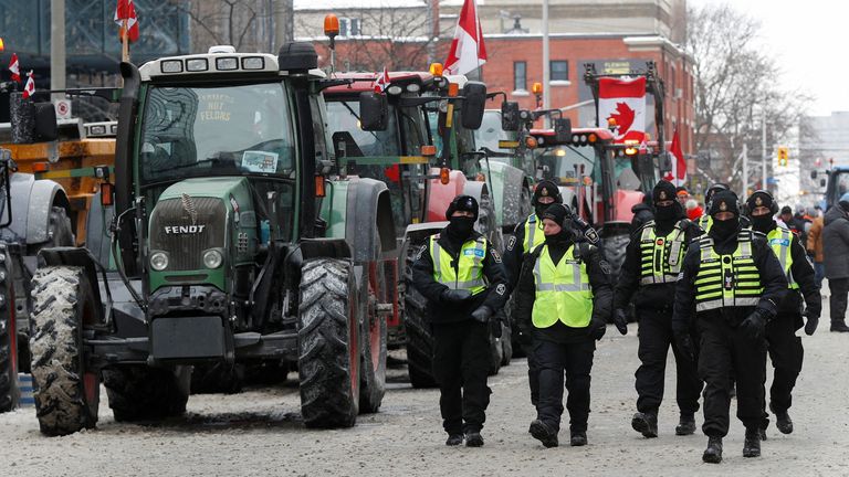 Police officers walk past parked tractors, as truckers and supporters continue to protest coronavirus disease (COVID-19) vaccine mandates, in Ottawa, Ontario, Canada, February 6, 2022. REUTERS/Lars Hagberg
