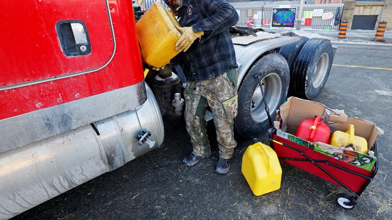 A demonstrator adds fuel to a truck gas tank as truckers and supporters continue to protest the coronavirus disease (COVID-19) vaccine mandates, in Ottawa, Ontario, Canada, February 14, 2022. REUTERS/Blair Gable
