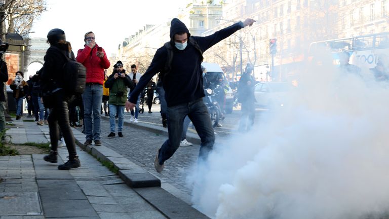 A demonstrator kicks in a tear gas grenade during a protest on the Champs-Elysees avenue, Saturday, Feb.12, 2022 in Paris. Paris police intercepted at least 500 vehicles attempting to enter the French capital in defiance of a police order to take part in protests against virus restrictions inspired by the Canada&#39;s horn-honking "Freedom Convoy." . (AP Photo/Adrienne Surprenant)


