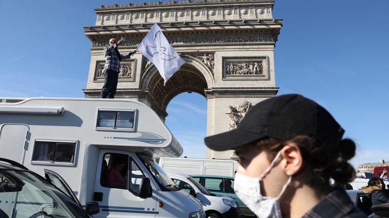 A protester stands atop a camper van as the convoy drives past the Arc de Triomphe on the Champs-Elysees avenue, Saturday, Feb.12, 2022 in Paris. Paris police intercepted at least 500 vehicles attempting to enter the French capital in defiance of a police order to take part in protests against virus restrictions inspired by the Canada&#39;s horn-honking "Freedom Convoy." . (AP Photo/Adrienne Surprenant)


