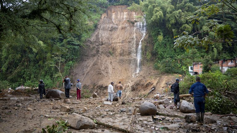 People stand next a landslide caused by heavy rains, that killed and injured residents and destroyed homes, in Pereira, Colombia, February 8, 2022. REUTERS/Vladimir Encina Duque NO RESALES. NO ARCHIVES
