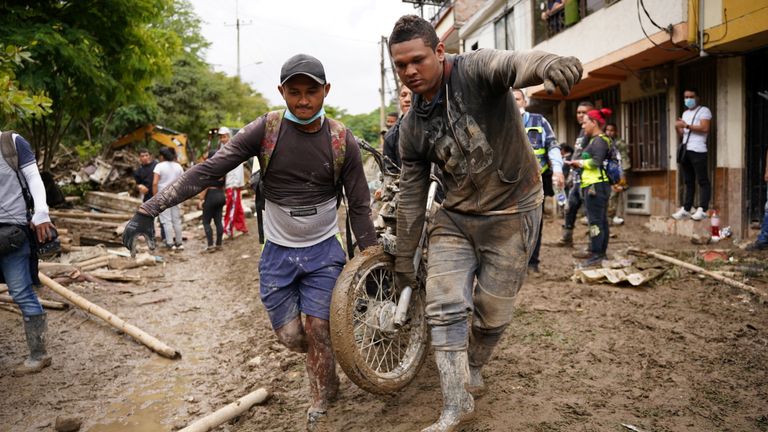 People remove a motorcycle following a landslide caused by heavy rains, that killed and injured residents and destroyed homes, in Pereira, Colombia, February 8, 2022. REUTERS/Vladimir Encina Duque NO RESALES. NO ARCHIVES
