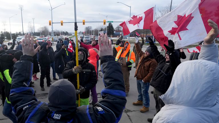 Protesters sing the Canadian national anthem prior to police action to enforce an injunction against a demonstration which has blocked traffic across the Ambassador Bridge by protesters against COVID-19 restrictions, in Windsor, Ont., Saturday, Feb. 12, 2022. THE CANADIAN PRESS/Nathan Denette