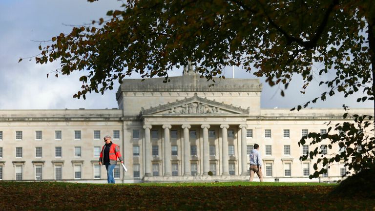 People walk past the grounds of Stormont estate beside Parliament buildings, in Belfast, Northern Ireland