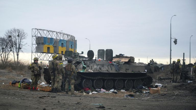 Ukrainian servicemen stand guard next to a destroyed armoured vehicle on the outskirts of Kharkiv, Ukraine February 25, 2022. REUTERS/Maksim Levin