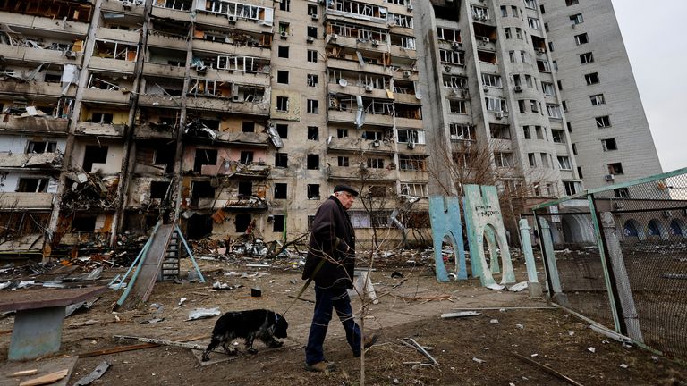 A person walks his dog in front of a damaged residential building, after Russia launched a massive military operation against Ukraine, in Kyiv, Ukraine February 25, 2022. REUTERS/Umit Bektas
