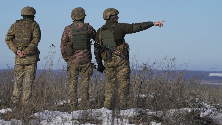 Ukrainian soldiers survey the impact of shells that landed close to their front line position over the border in Russia
