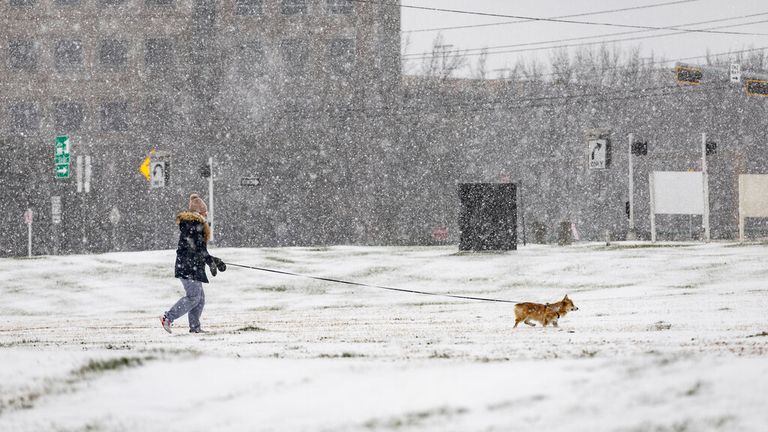 A woman walks her dog in Dallas after snow knocked out power in some homes in Texas