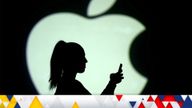 Silhouette of a mobile user seen next to a screen projection of the Apple logo in this picture illustration taken March 28, 2018. REUTERS/Dado Ruvic/Illustration/File Photo