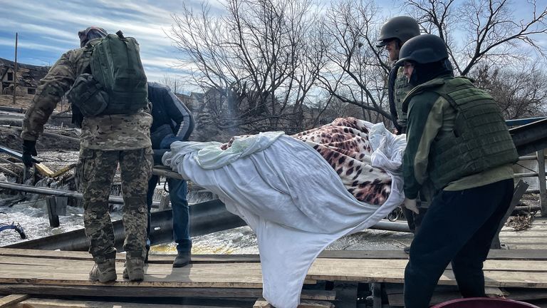 A body being carried away from Irpin over a destroyed bridge