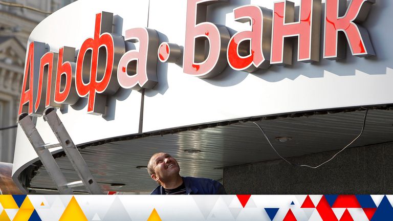 A worker looks up at a signboard being installed outside an Alfa-Bank office in central Moscow 