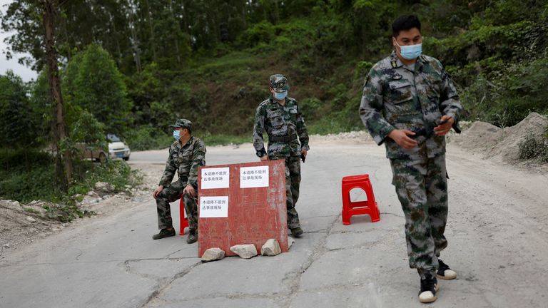 Militia members stand guard at the checkpoint on the road next to the entrance to Lu village near the site where a China Eastern Airlines Boeing 737-800 plane flying from Kunming to Guangzhou crashed, in Wuzhou, Guangxi Zhuang Autonomous Region, China March 22, 2022. REUTERS/Carlos Garcia Rawlins
