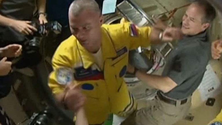 Astronauts docked in the ISS in yellow and blue suits