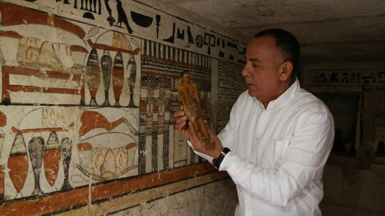 Mostafa Waziri shows a small statue at one of the recently discovered tombs