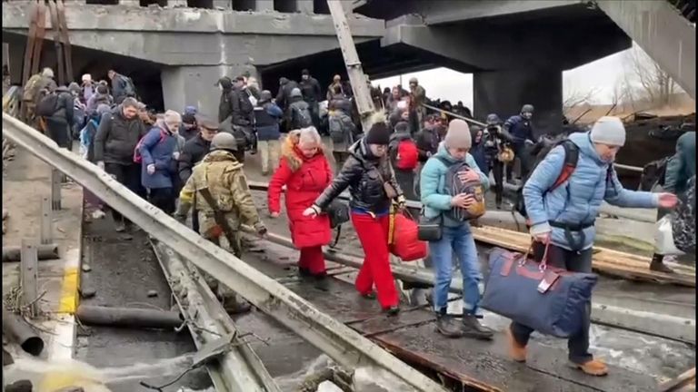 Civilians flee over a destroyed bridge near Kyiv