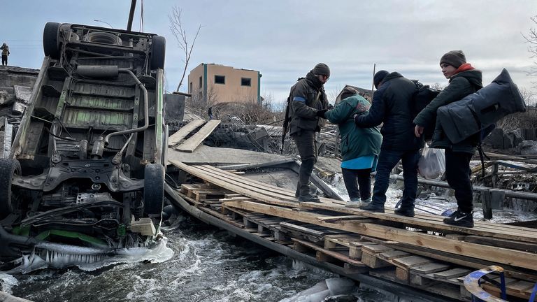 Families being evacuated from Irpin crossing a destroyed bridge