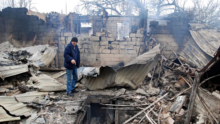 A man stands on the rubble of a house destroyed by shelling in Kharkiv