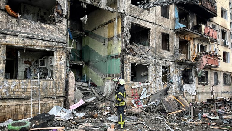 Un officier des pompiers aide les gens à déplacer leurs biens des appartements en ruine