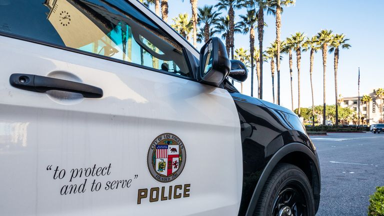 Los Angeles, USA - Close-up on the insignia and slogan of a LAPD vehicle, with the reflection of Union Station&#39;s tower visible in the car&#39;s window.