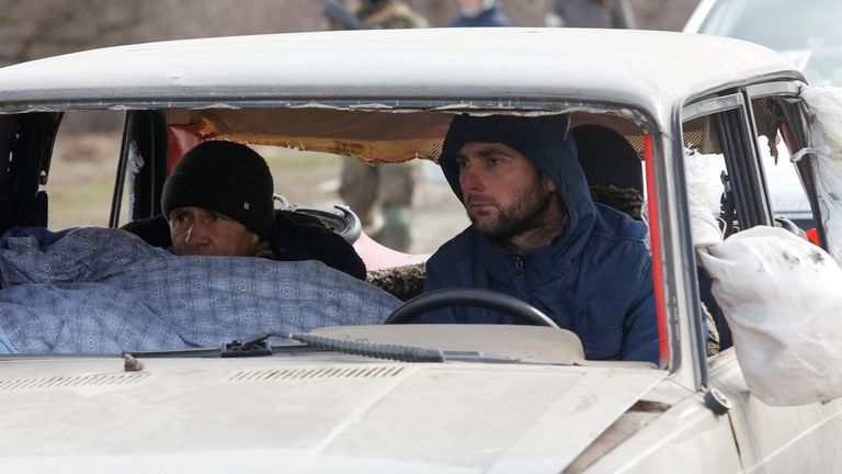 Evacuees fleeing Ukraine-Russia conflict sit in a damaged car as they wait in a line to leave the besieged southern port city of Mariupol, Ukraine March 17, 2022. REUTERS/Alexander Ermochenko

