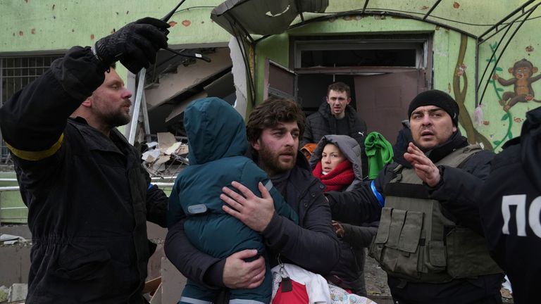 Un homme emmène son enfant loin de la maternité endommagée par les bombardements à Marioupol, en Ukraine, le mercredi 9 mars 2022. Une attaque russe a gravement endommagé une maternité dans la ville portuaire assiégée de Marioupol, selon des responsables ukrainiens.  (AP Photo/Evgeny Maloletka)