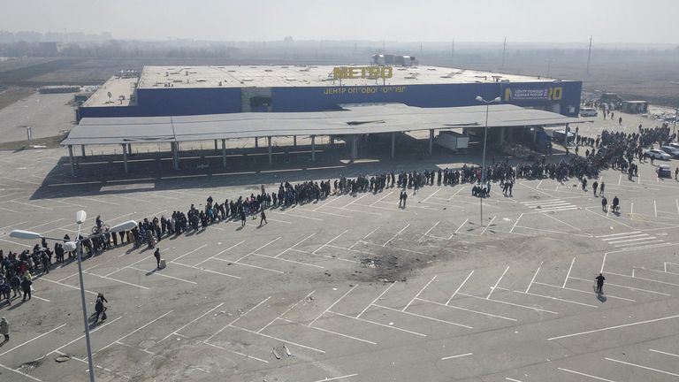 People stand in a long queue during the distribution of humanitarian aid near a damaged store of wholesaler Metro in the course of Ukraine-Russia conflict in the besieged southern port city of Mariupol, Ukraine March 24, 2022. Picture taken with a drone. REUTERS/Pavel Klimov
