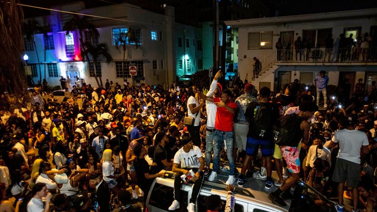 Crowds gather in the street while a speaker blasts music an hour past curfew in Miami Beach, Fla., on Sunday, March 21, 2021. Pic: Daniel A. Varela/Miami Herald via AP