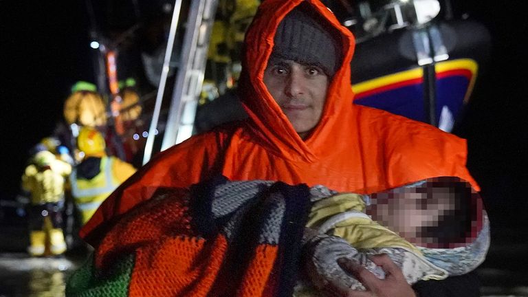 A man carries a young child as a group of people thought to be migrants are brought in to Dungeness, Kent, after being rescued by the RNLI lifeboat following a small boat incident in the Channel. Picture date: Saturday January 15, 2022.