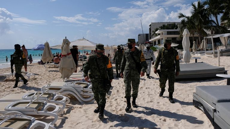 Turistai stebi grupę kareivių, patruliuojančių teritorijoje už Mamita & # 39; s Beach Club, praėjus kelioms valandoms po to, kai žudikai nužudė baro vadovą, Plaja del Karmen mieste, Meksikoje, 2022 m. sausio 26 d. REUTERS / Paola Chiomant