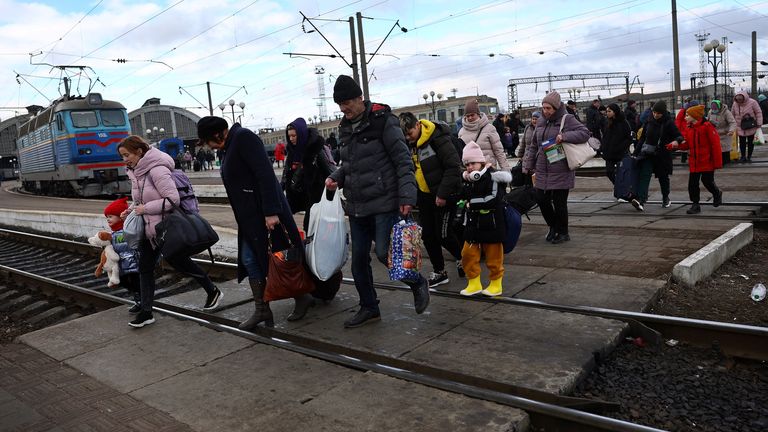 Refugees fleeing the ongoing Russian invasion of Ukraine cross the tracks after arriving on a train from Kyiv region at the train station in Lviv, Ukraine, March 8, 2022. REUTERS/Kai Pfaffenbach

