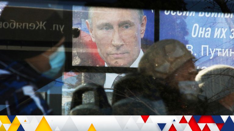 A board with the portrait of Russian President Vladimir Putin is seen through a bus window in Simferopol, Crimea March 11, 2022. REUTERS/Alexey Pavlishak