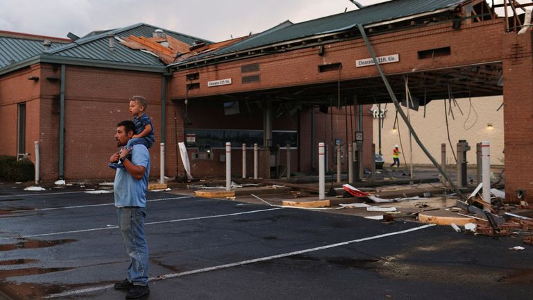 Arturo Ortega and his son Kaysen Ortega, 2, survey the damage to a shopping center after a tornado in a widespread storm system touched down in Round Rock, Texas, U.S., March 21, 2022. REUTERS/Tamir Kalifa
