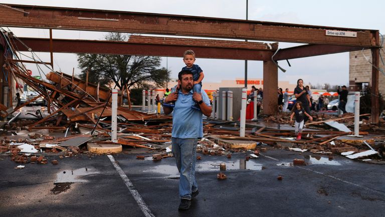Arturo Ortega and his son Kaysen Ortega, 2, survey the damage to a shopping center after a tornado in a widespread storm system touched down in Round Rock, Texas, U.S., March 21, 2022. REUTERS/Tamir Kalifa 