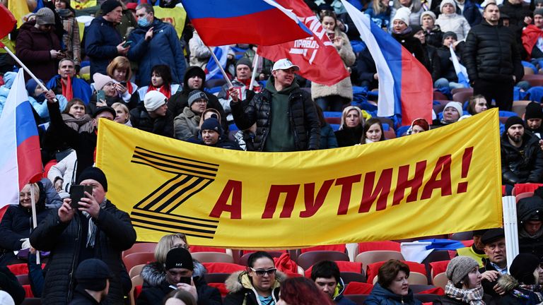 People in the crowd hold a banner reading &#39;For Putin!" during a concert marking the eighth anniversary of Russia&#39;s annexation of Crimea at the Luzhniki Stadium in Moscow, Russia