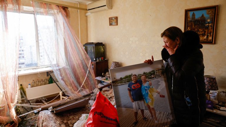 Tatyana Vaskovskaya packs a family photo as she gathers her belongings to evacuate her apartment after her residential building was hit by an intercepted missile, following Russia&#39;s invasion of Ukraine,  in Kyiv, Ukraine March 17, 2022. REUTERS/Thomas Peter
