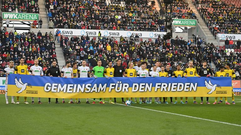 German teams pose for a photo with a sign saying &#39;together for peace&#39;.