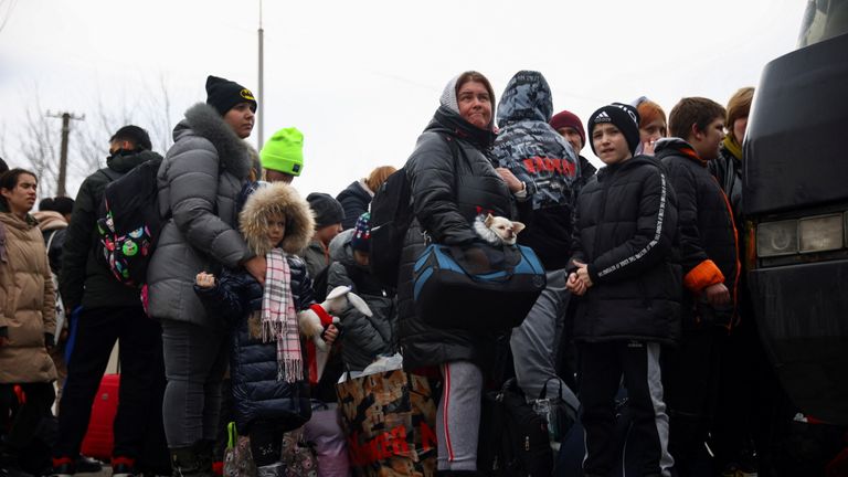 People fleeing Russia&#39;s invasion of Ukraine, of which one carries a dog, attempt to enter a bus to Poland at a long distance bus terminal in Lviv, Ukraine March 2, 2022. REUTERS/Thomas Peter