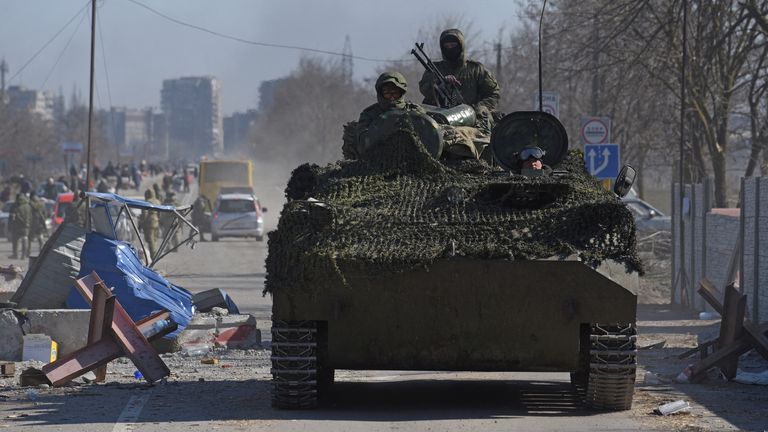 Service members of pro-Russian troops drive an armoured vehicle in Mariupol