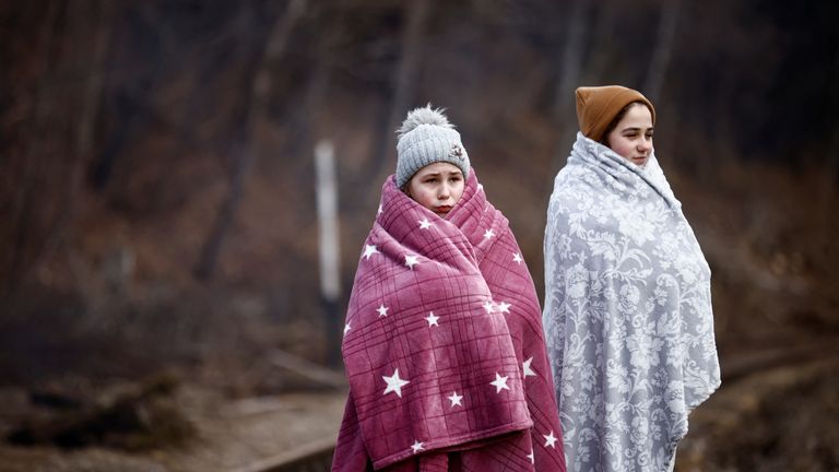Young girls stand near a railway track after crossing the border between Poland and Ukraine, in Kroscienko