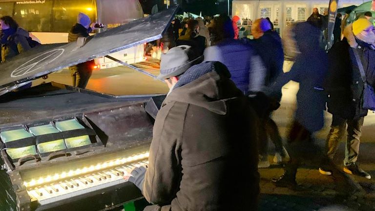 A charity worker plays the piano to try to bring some cheer to the displaced