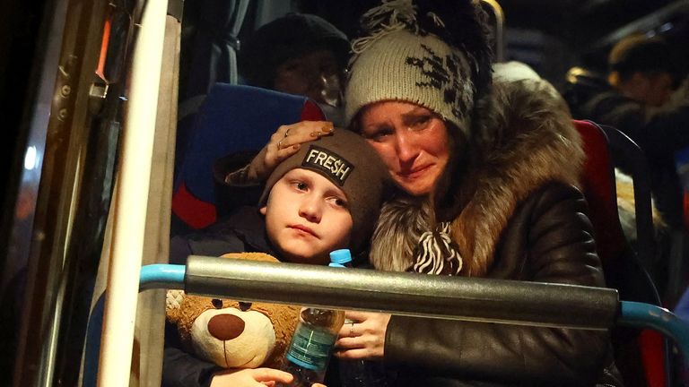 A woman cries as she comforts her son and prepares to leave a bus taking orphans fleeing the ongoing Russian invasion outside Lviv station