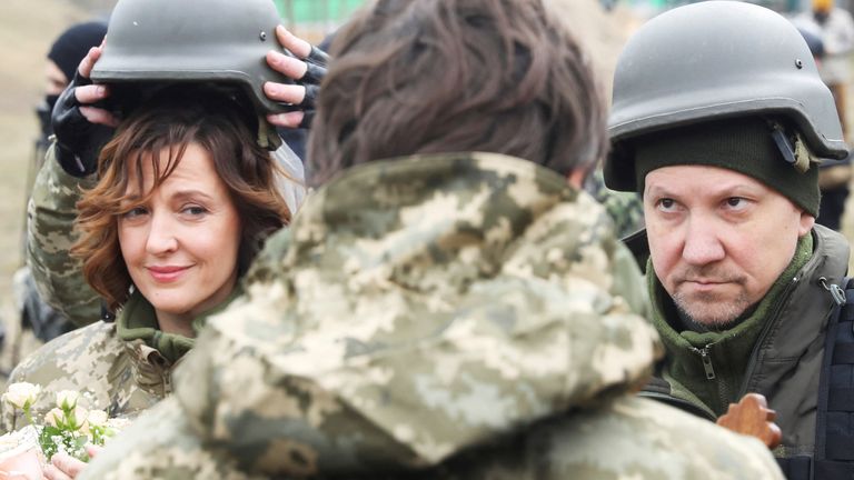 Members of the Ukrainian Territorial Defence Forces, Lesia Ivashchenko and Valerii Fylymonov, listen to a priest at their wedding at a checkpoint in Kyiv